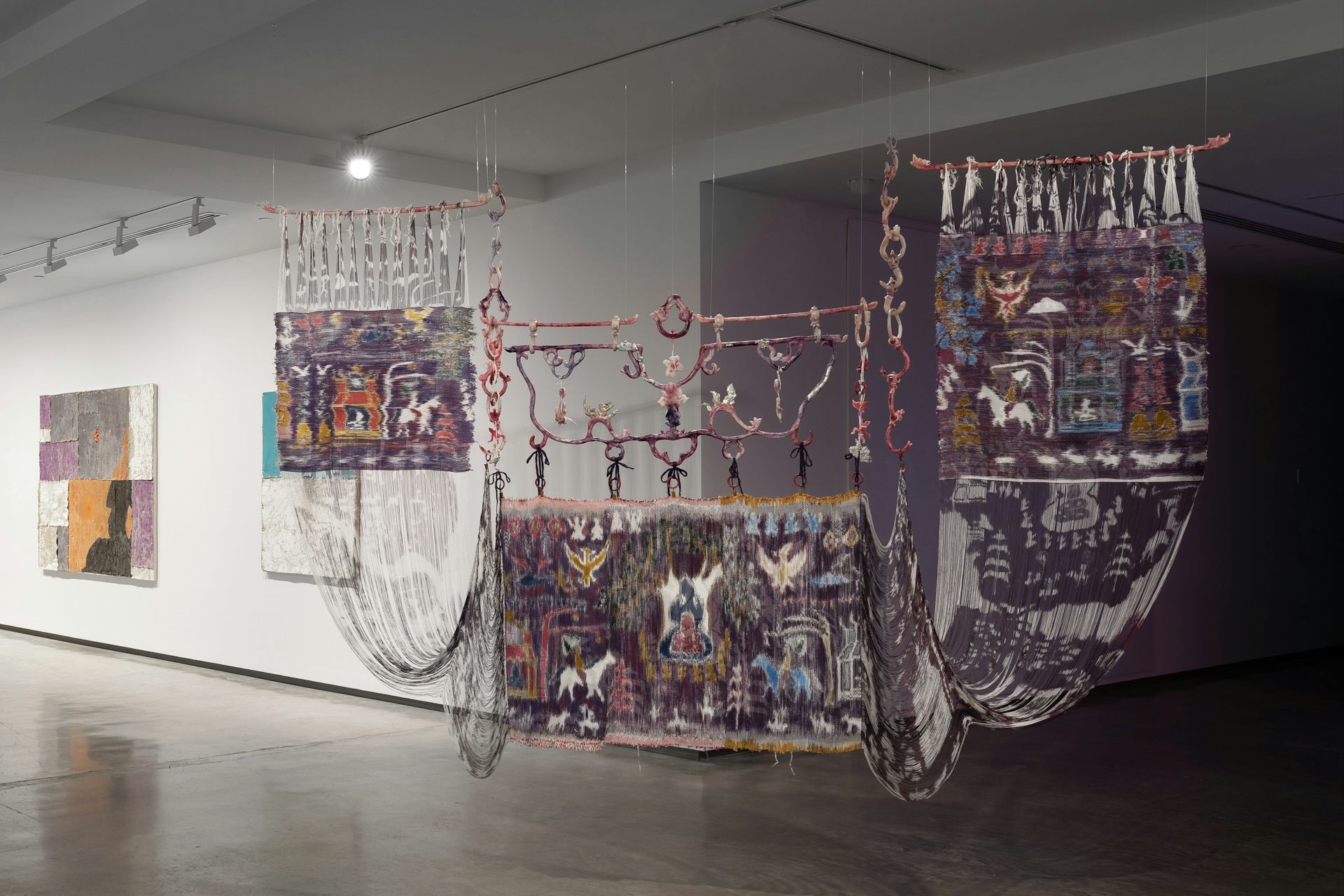 Three weavings hang in a gallery.