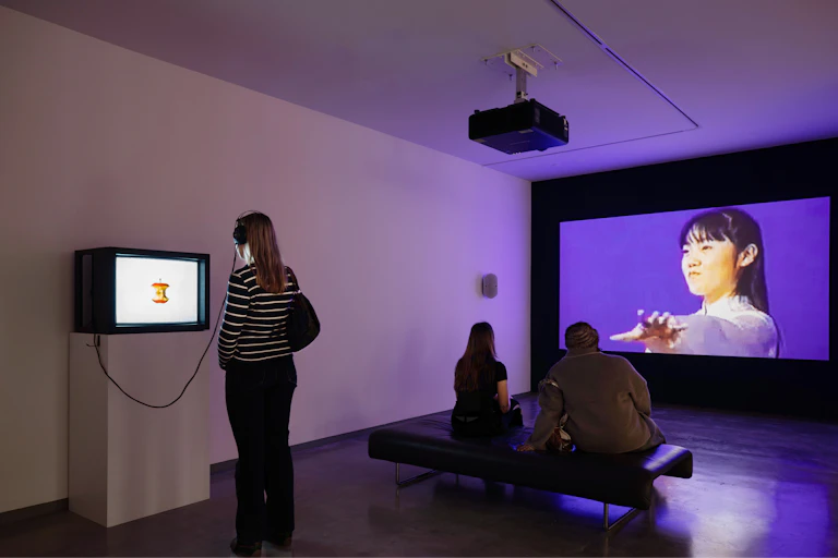 Visitors look at various sized screens in a gallery.