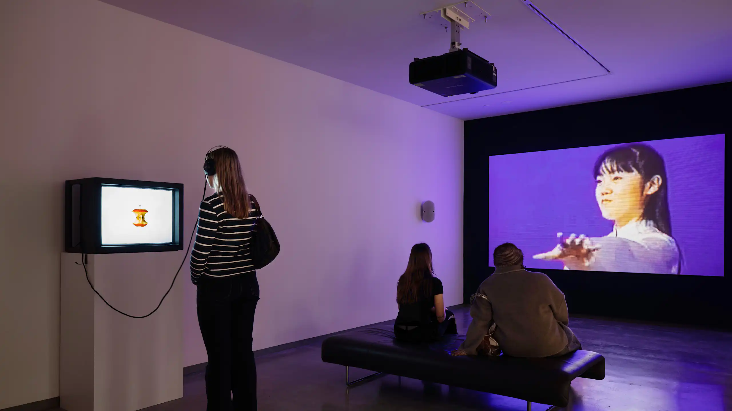 Visitors look at various sized screens in a gallery.