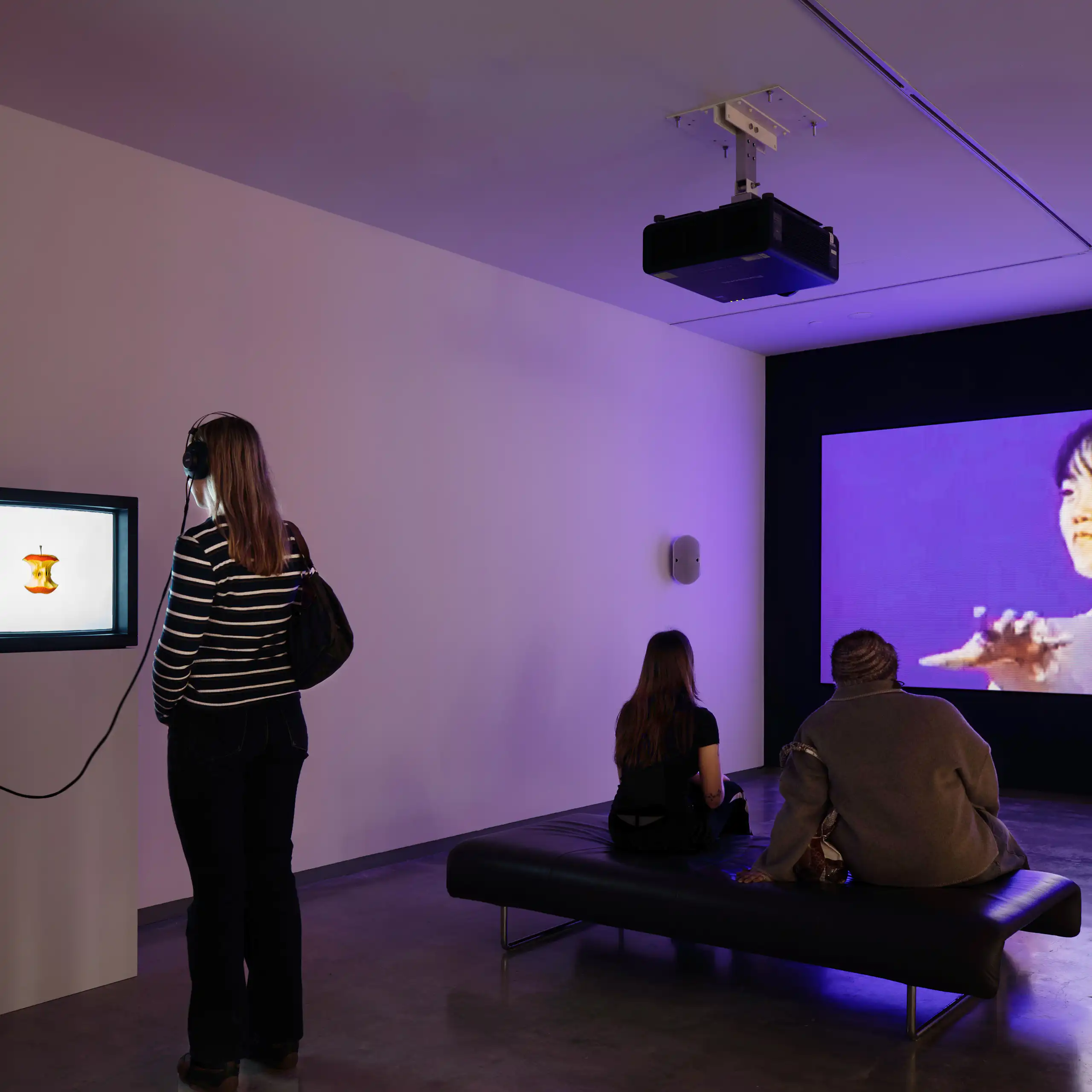 Visitors look at various sized screens in a gallery.