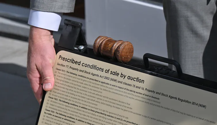 An auctioneer's gavel is seen resting on a sign