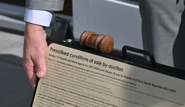 An auctioneer's gavel is seen resting on a sign