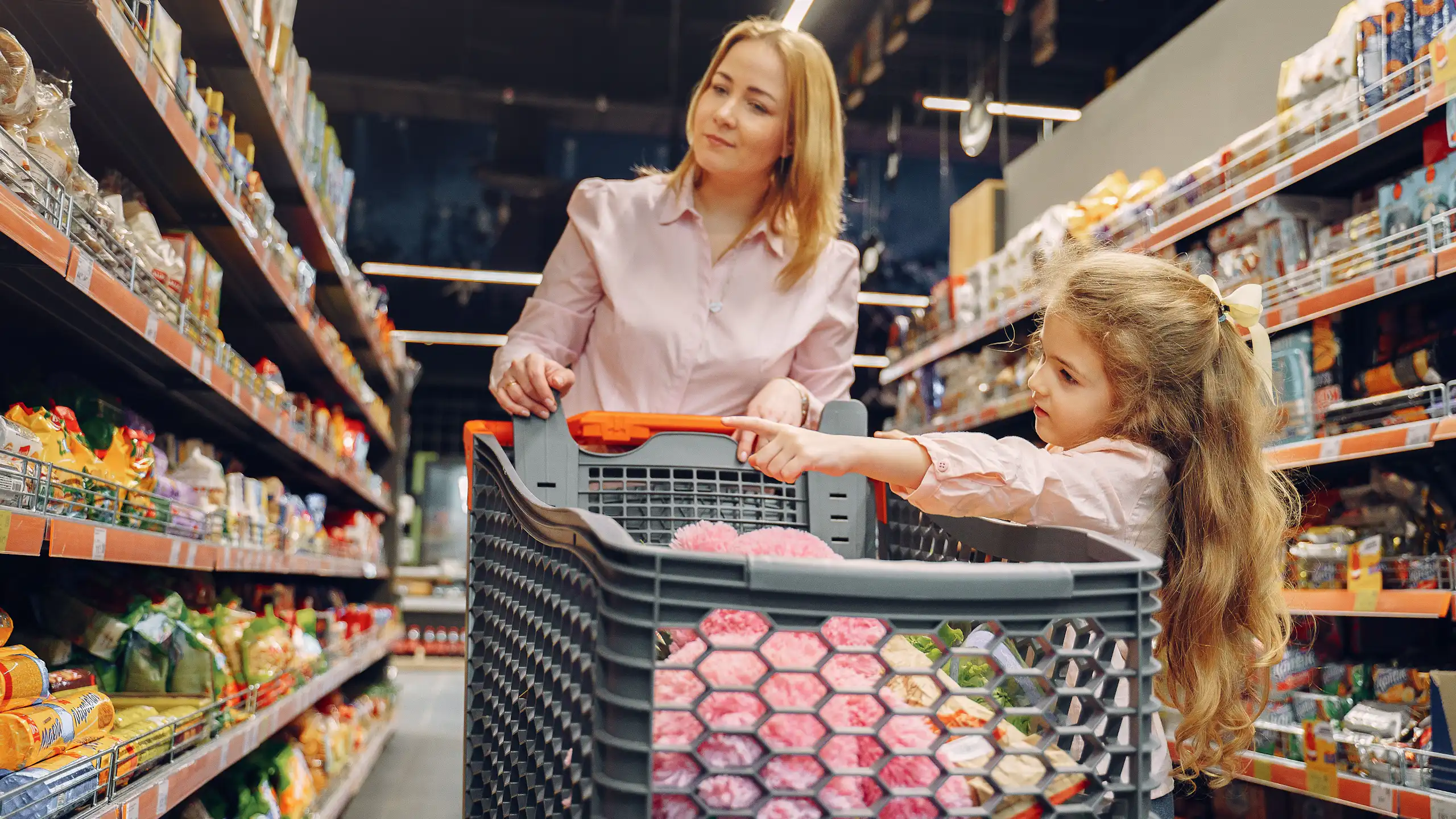 A mother and daughter enjoying time together shopping in a vibrant supermarket aisle.