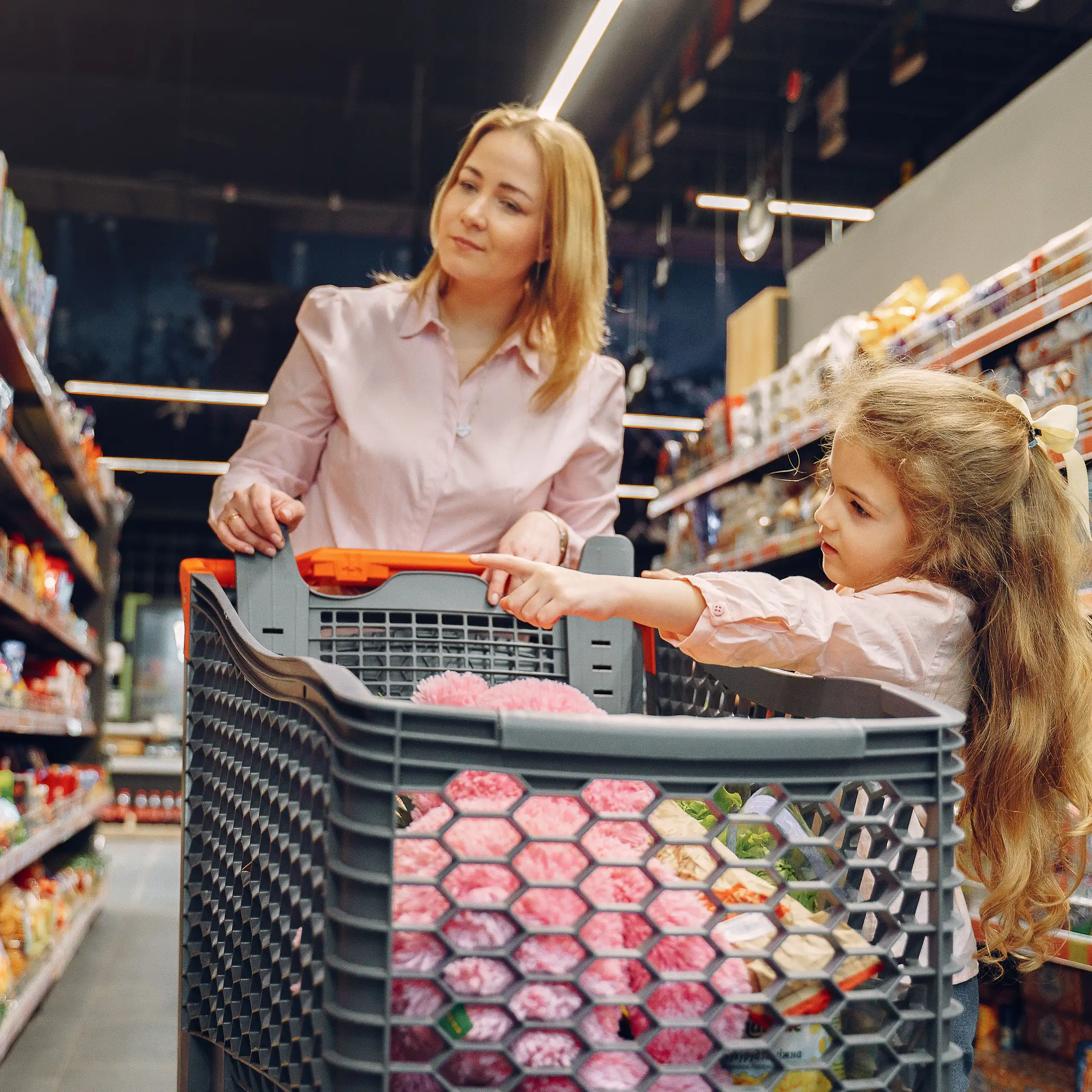 A mother and daughter enjoying time together shopping in a vibrant supermarket aisle.