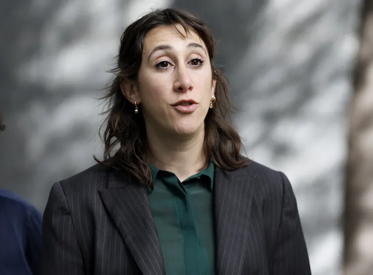 a woman in a black suit jacket and green shirt