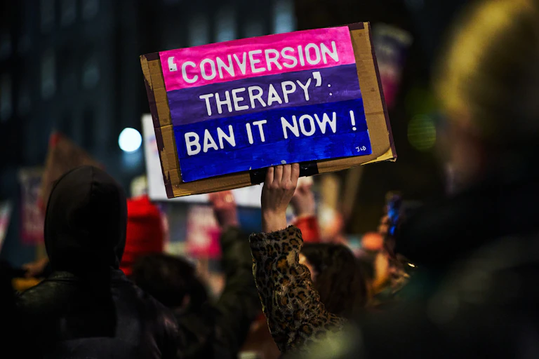 Protester holding a card that says: 'Conversion therapy: ban it now!'