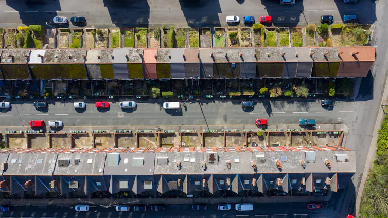 aerial shot looking down to straight streets of old houses with small gardens and cars parked