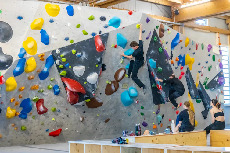 A climber being watched by two women.