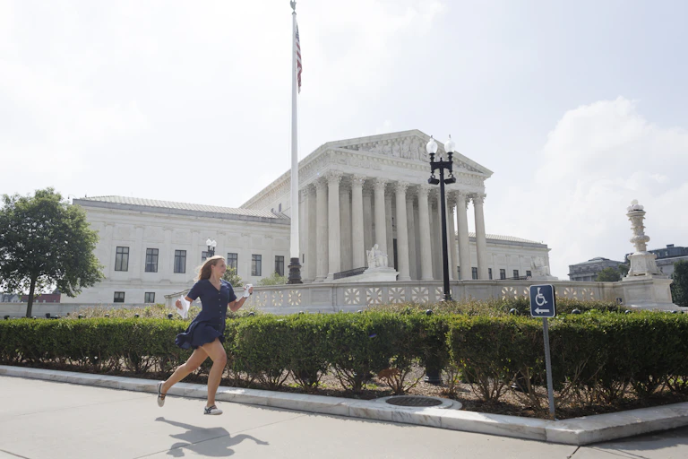 A woman holding paper in her hand runs by a federal building.