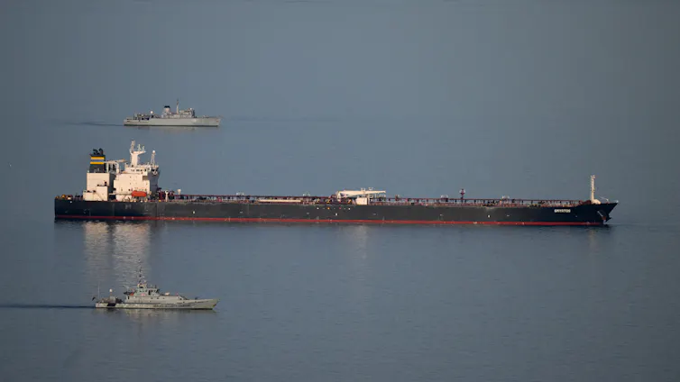 Two military ships escort a large tanker