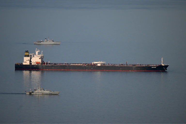 Two military ships escort a large tanker