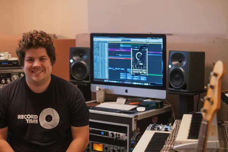Un musicien dans son studio de musique regarde l’objectif