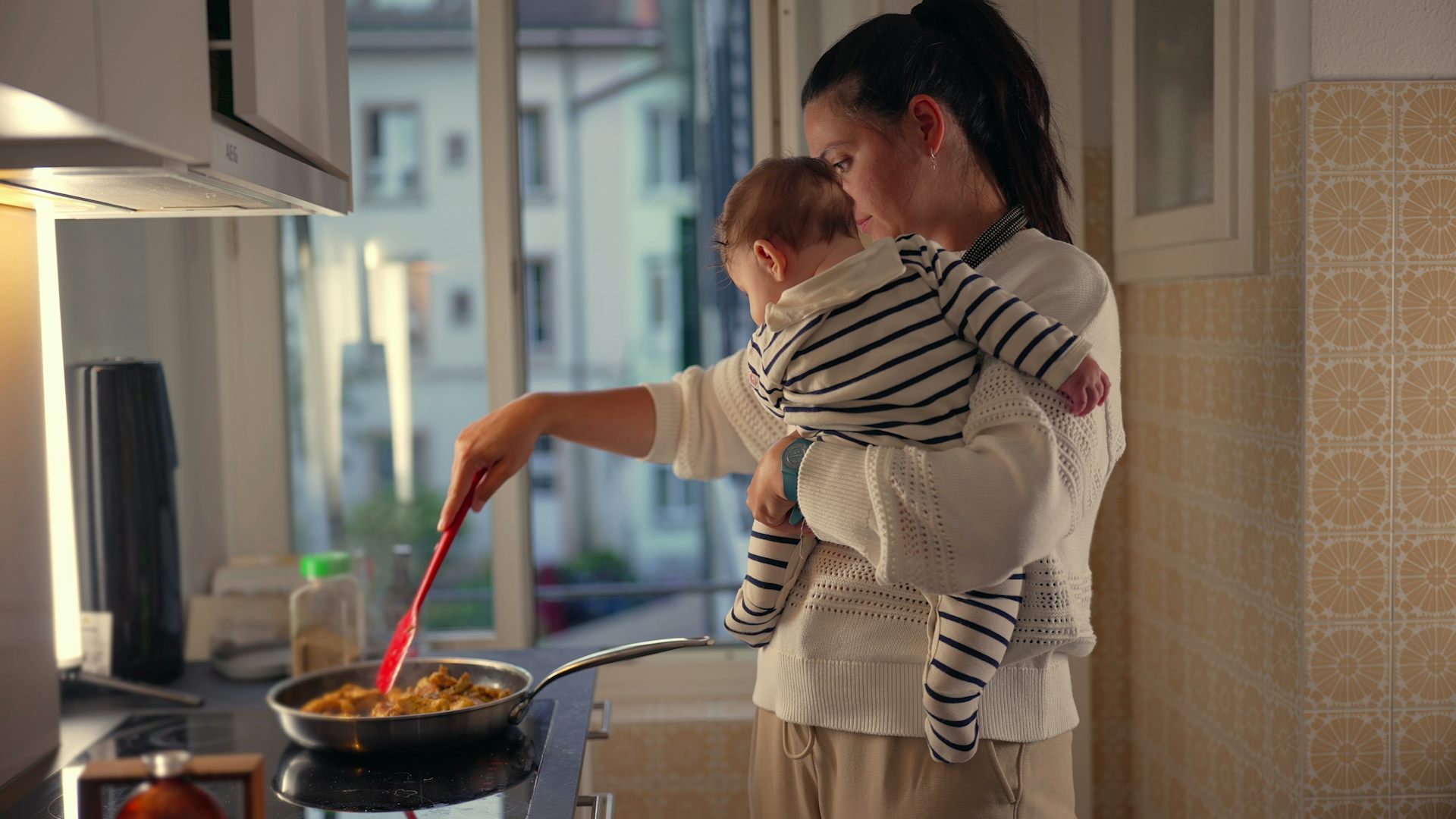 Mother holding baby and cooking
