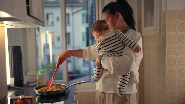Mother holding baby and cooking