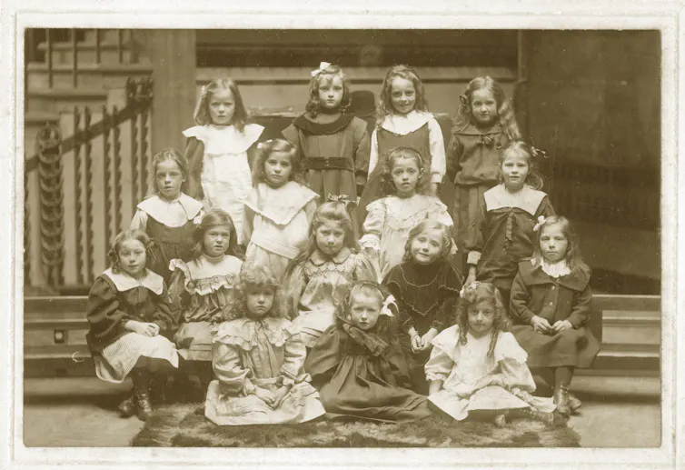 A group photo of Victorian schoolgirls arranged in rows, taken around 1900.