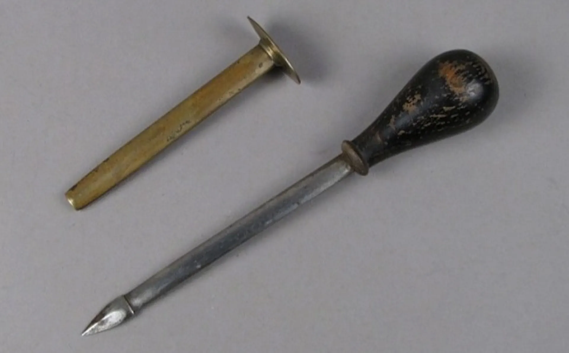 two metal tools side by side, one more like a tube and one with a sharp point