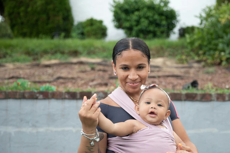 A woman with a baby strapped to her front.