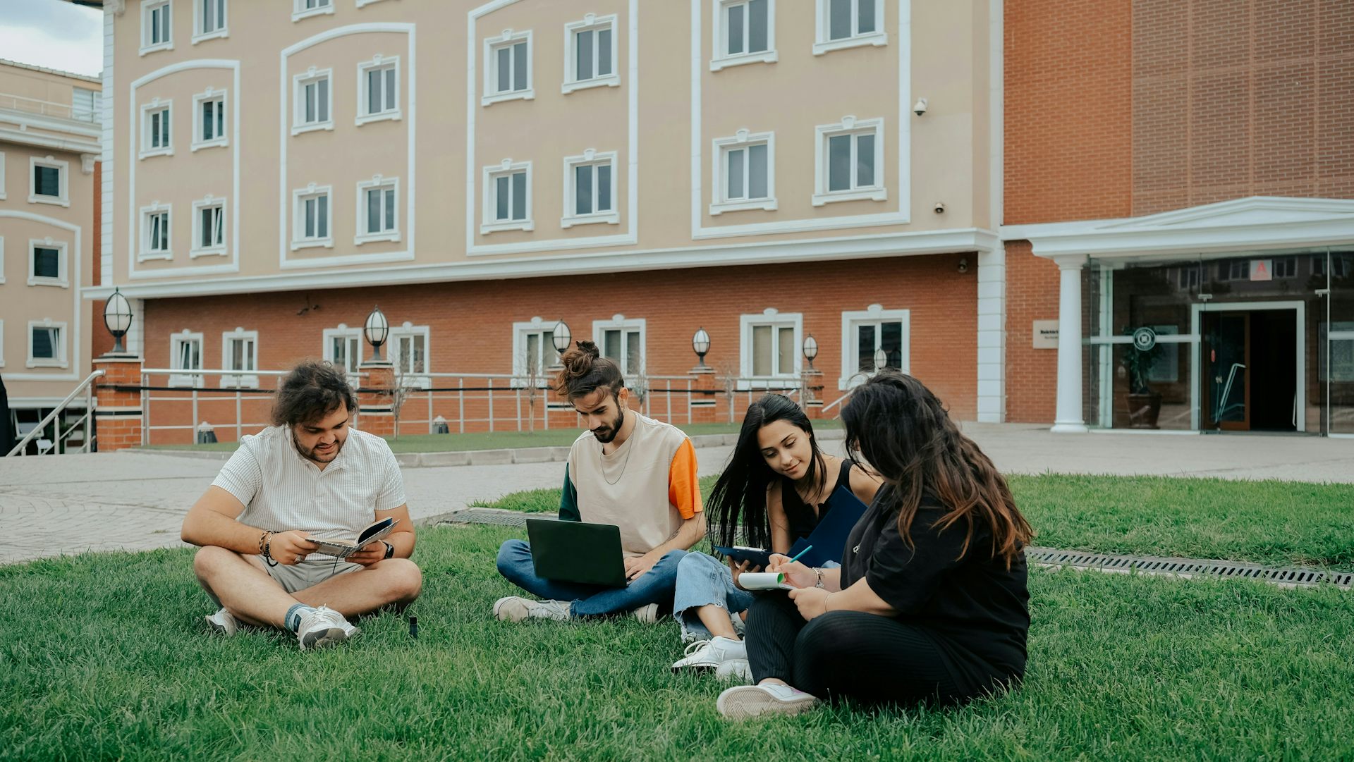 Los estudiantes se sientan en el césped del campus.