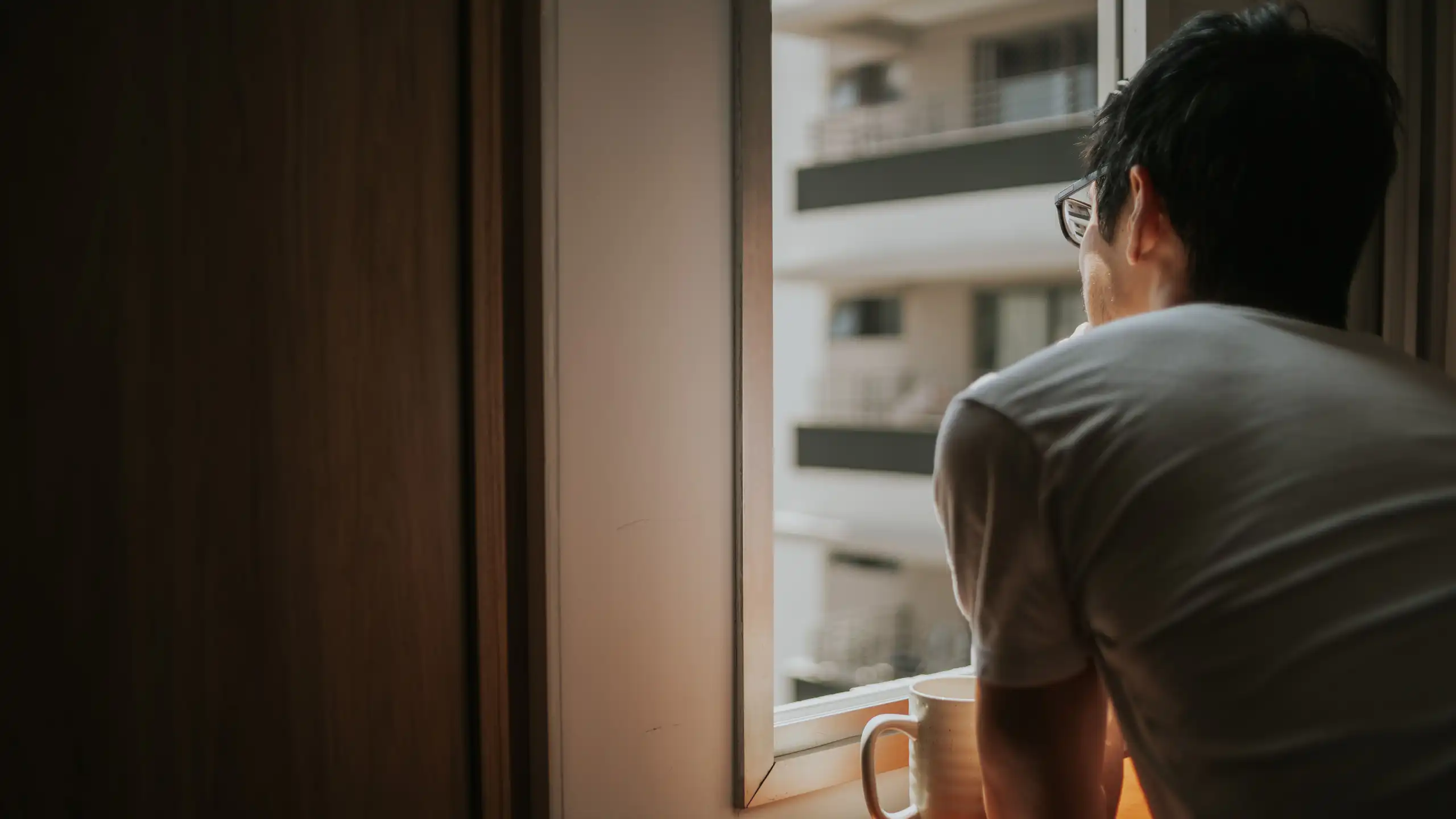 A man looks out an apartment window