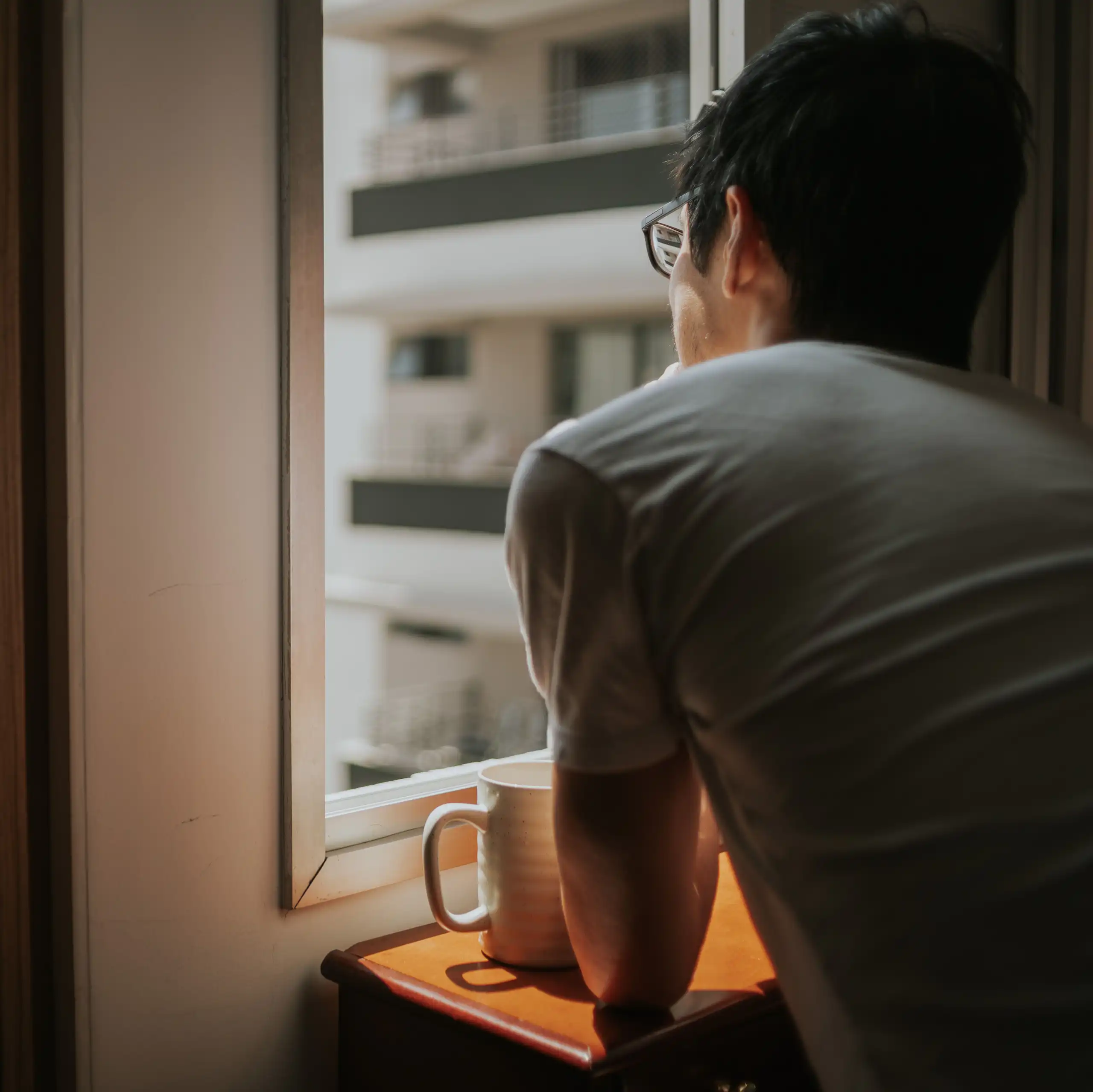 A man looks out an apartment window