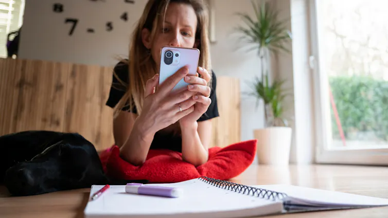 Woman looking at phone with study notes