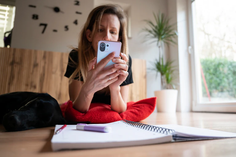 Woman looking at phone with study notes