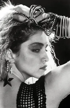 Madonna around the age of 25 wearing lots of cheap bangles and earrings.