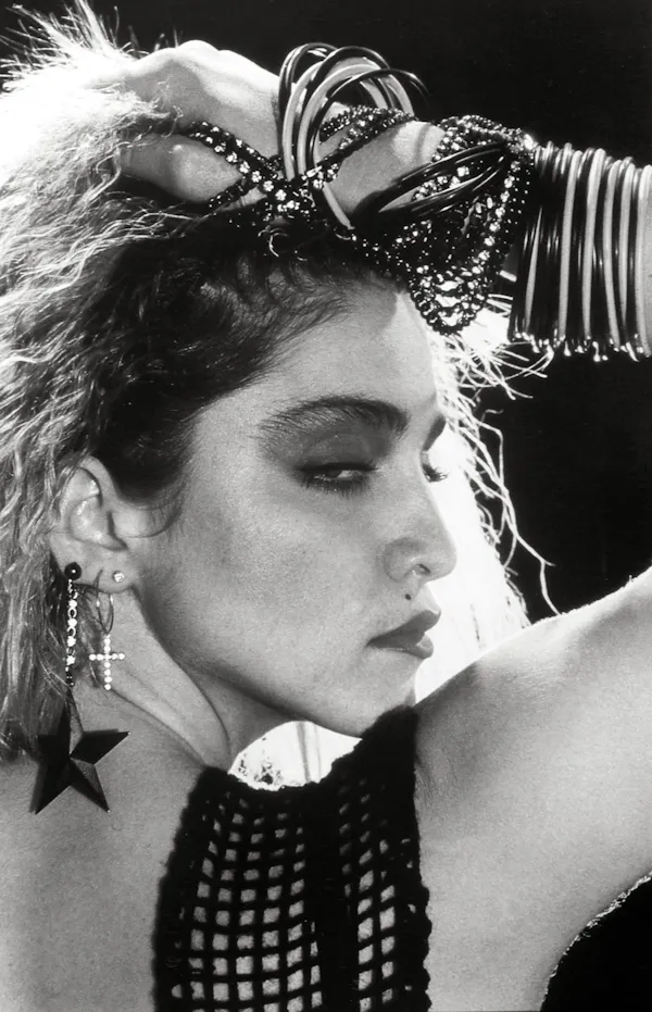 Madonna around the age of 25 wearing lots of cheap bangles and earrings.
