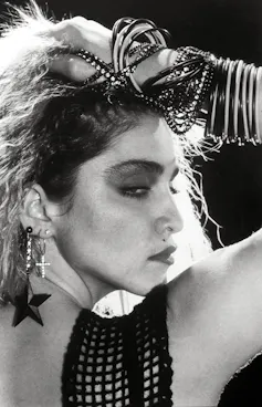 Madonna around the age of 25 wearing lots of cheap bangles and earrings.