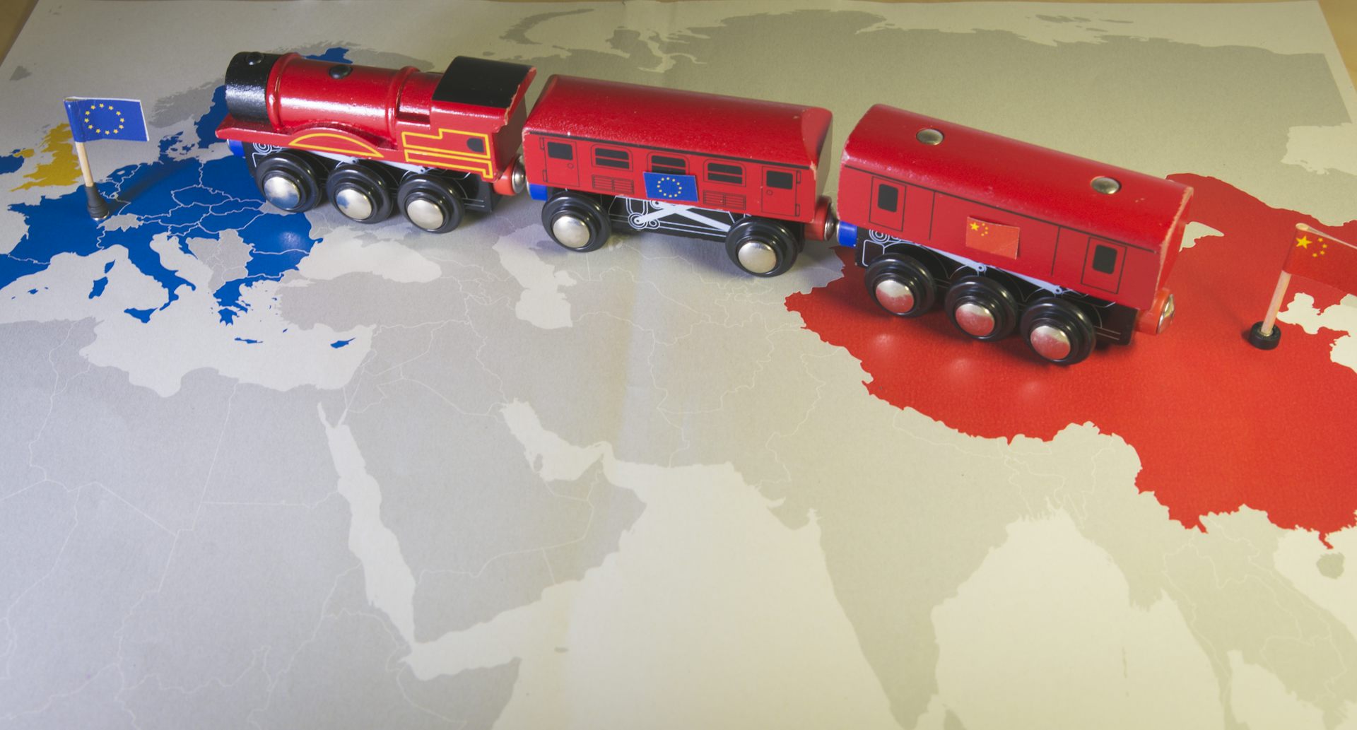 Morceau de planisphère visualisant, à l’ouest, les pays membres de l'Union européenne, signalés en bleu, et, à l'est, la Chine, en rouge. Un train rouge portant les deux drapeaux (UE et Chine) circule de l'est à l'ouest