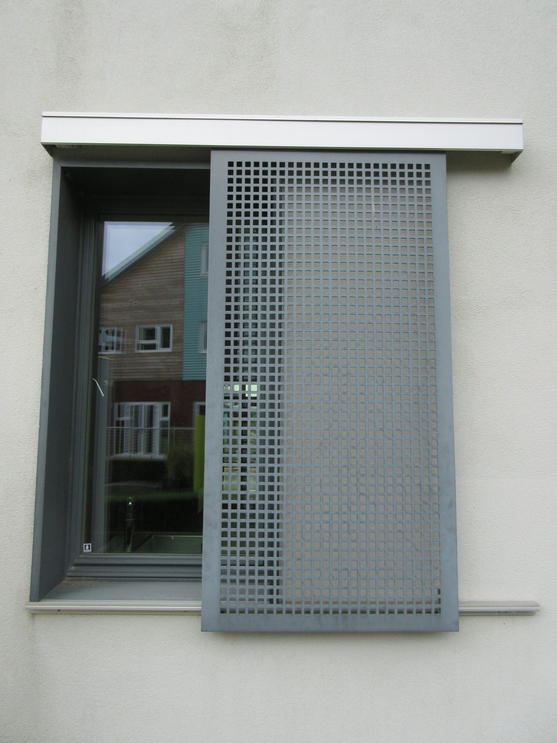 A window with a grey grille in front.