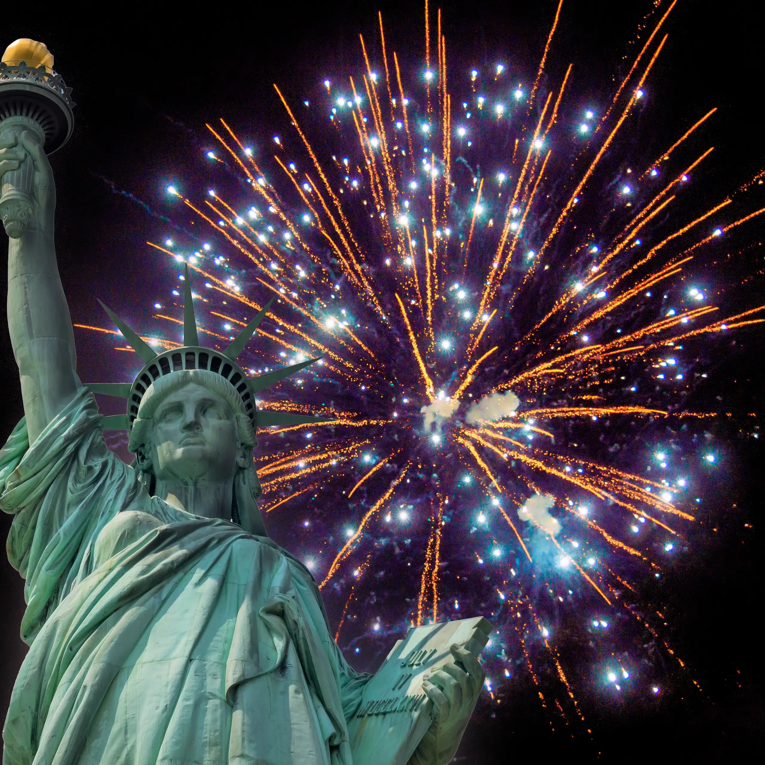 The Statue of Liberty against a skyline of 4th of July fireworks in New York.