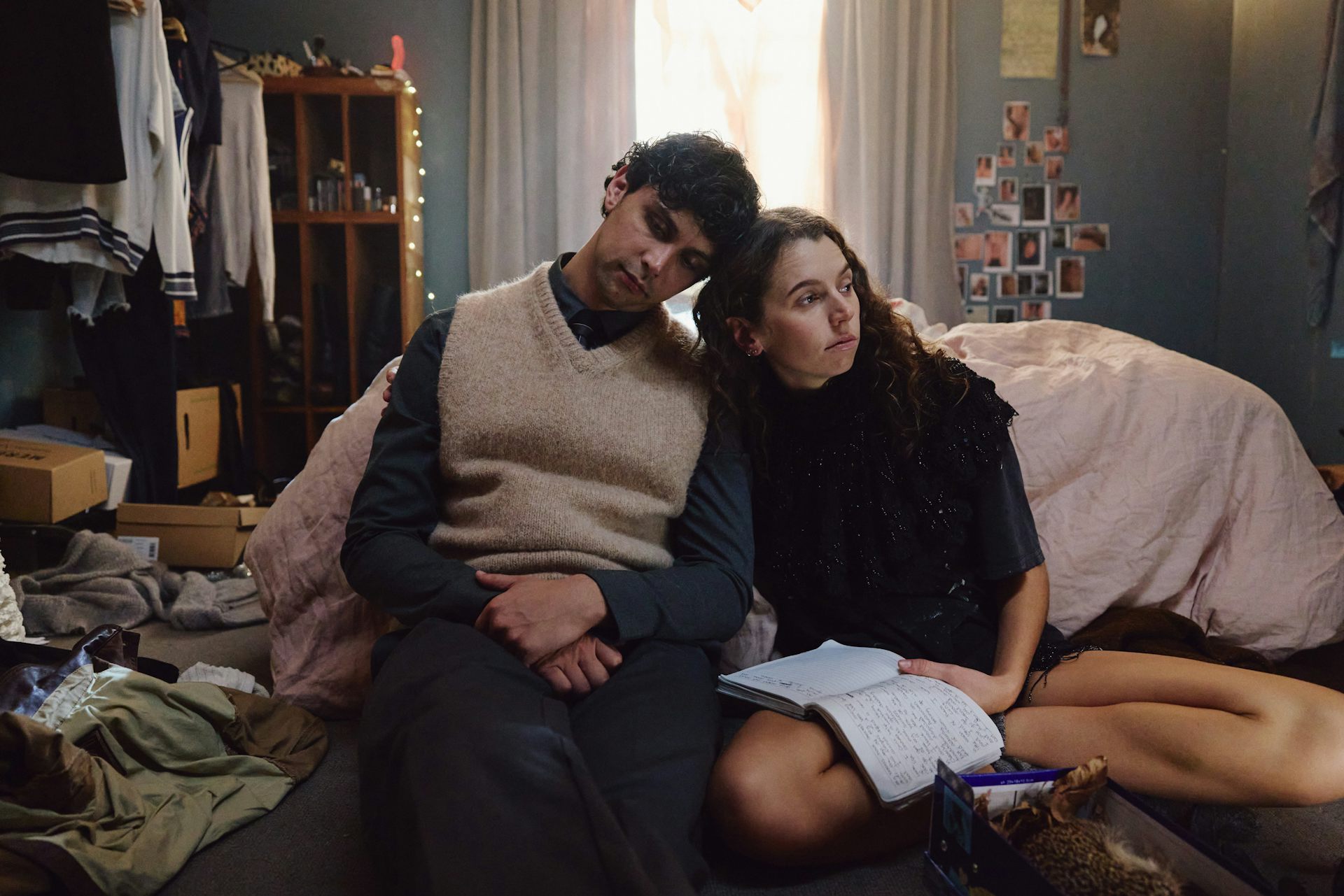 A couple lean on each other in a messy bedroom