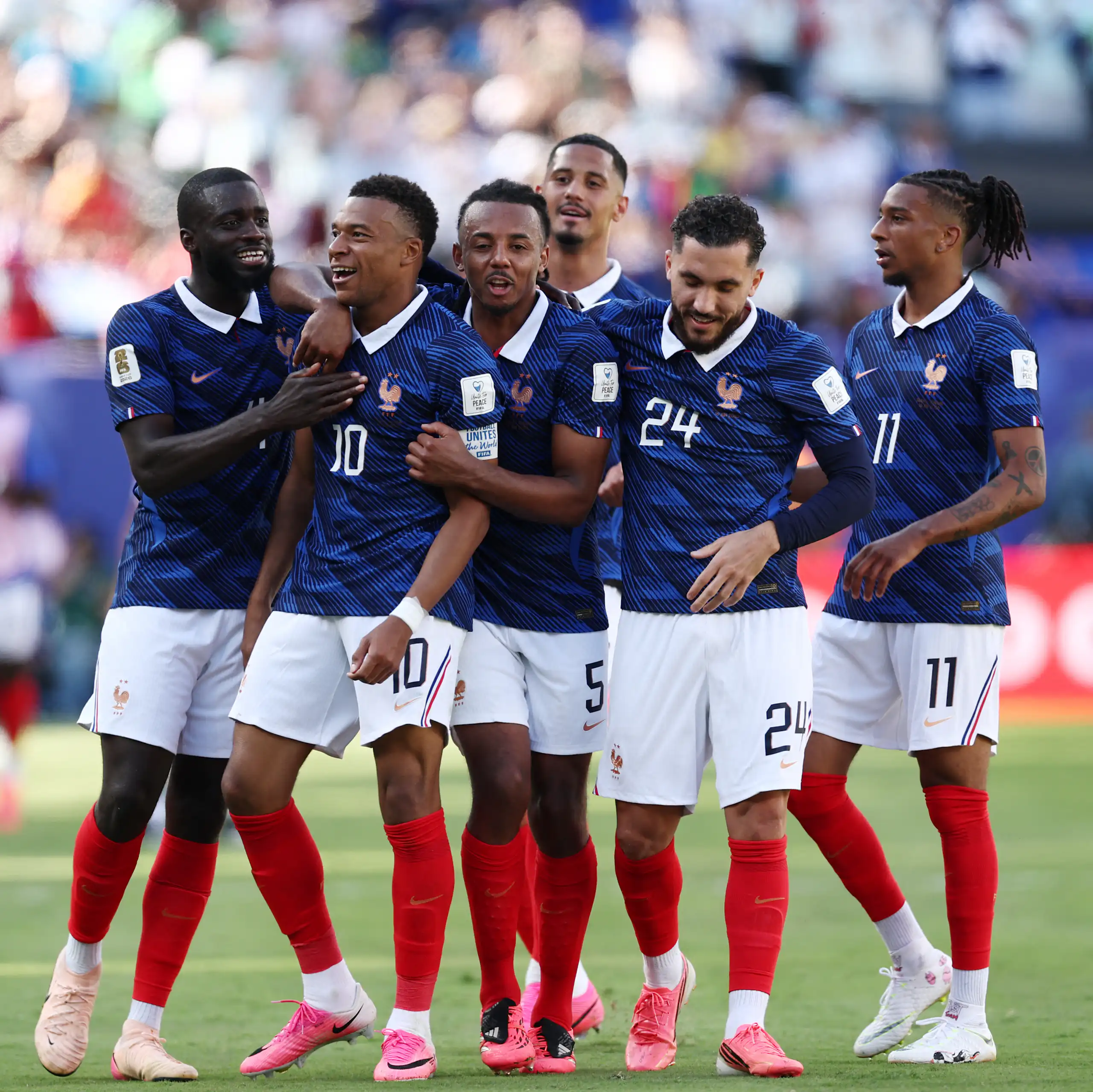 Kylian Mbappé et ses coéquipiers s’embrassant sur le terrain de foot.