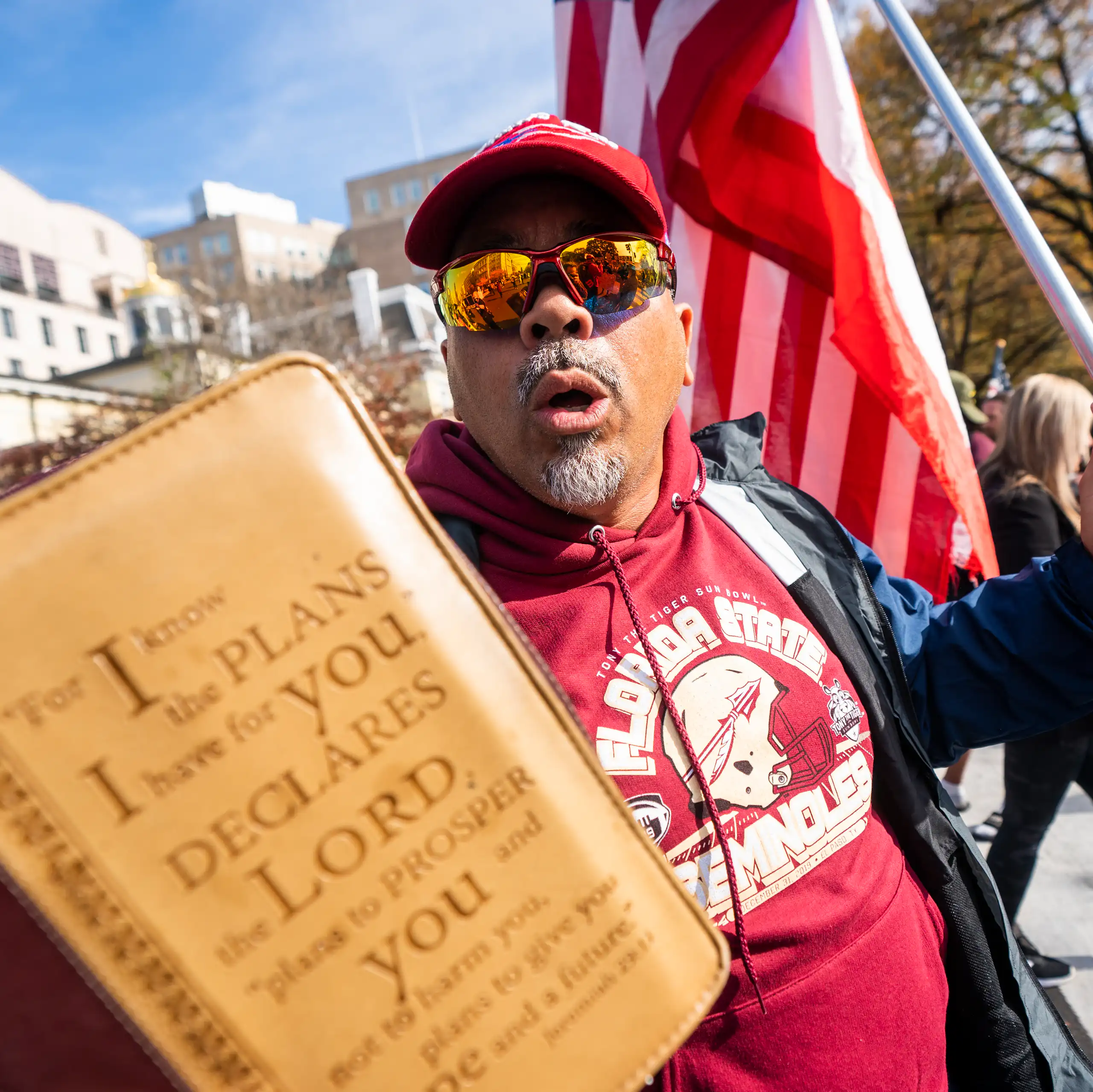 a supporter of president donald trump waves a bible and us flag outside the white house.