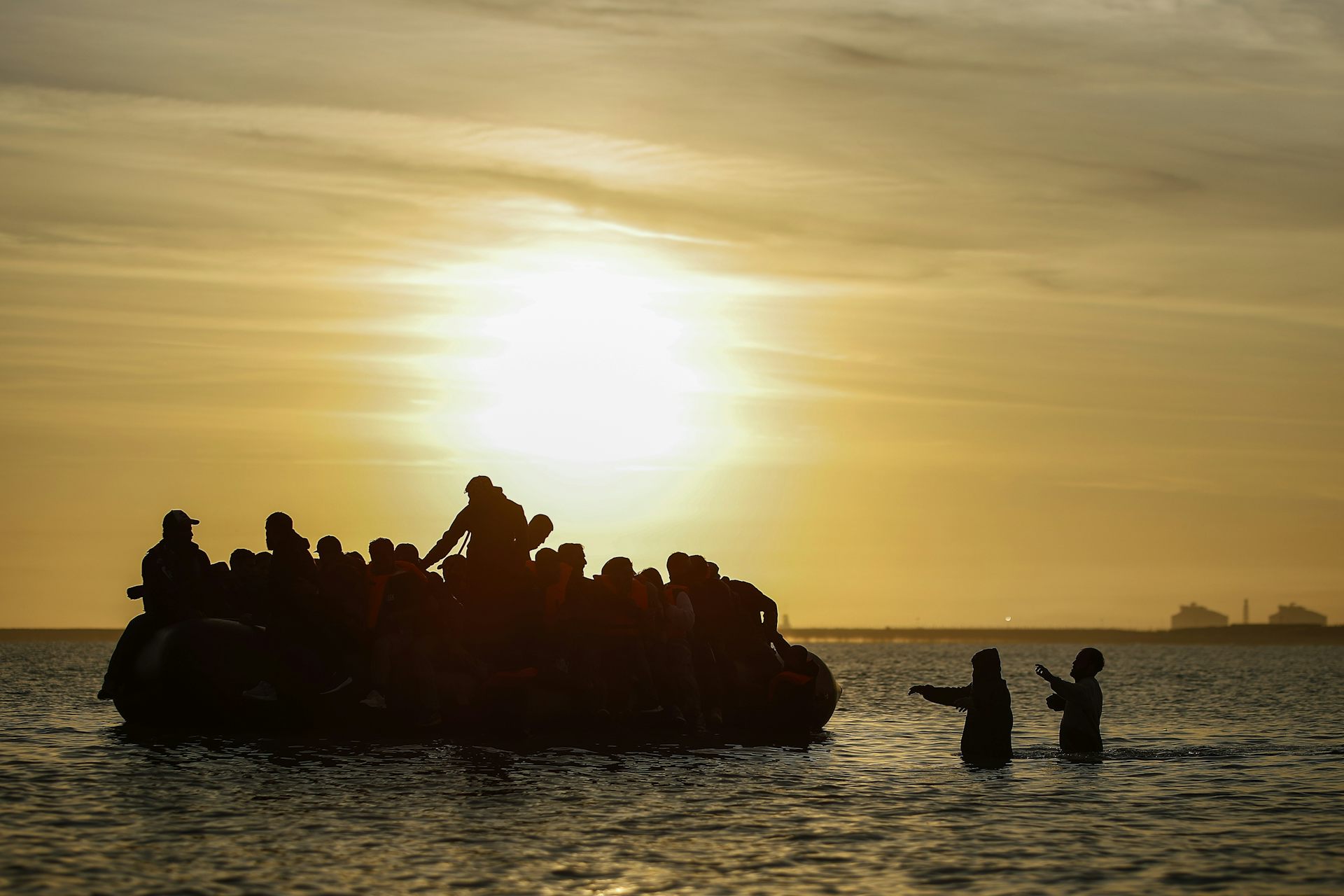 Silhouette of a small boat full of people in the sea in northern France