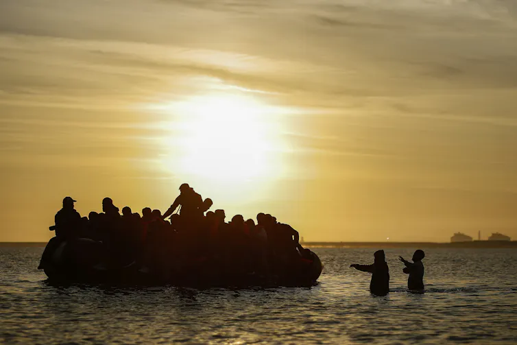 Silhouette of a small boat full of people in the sea in northern France