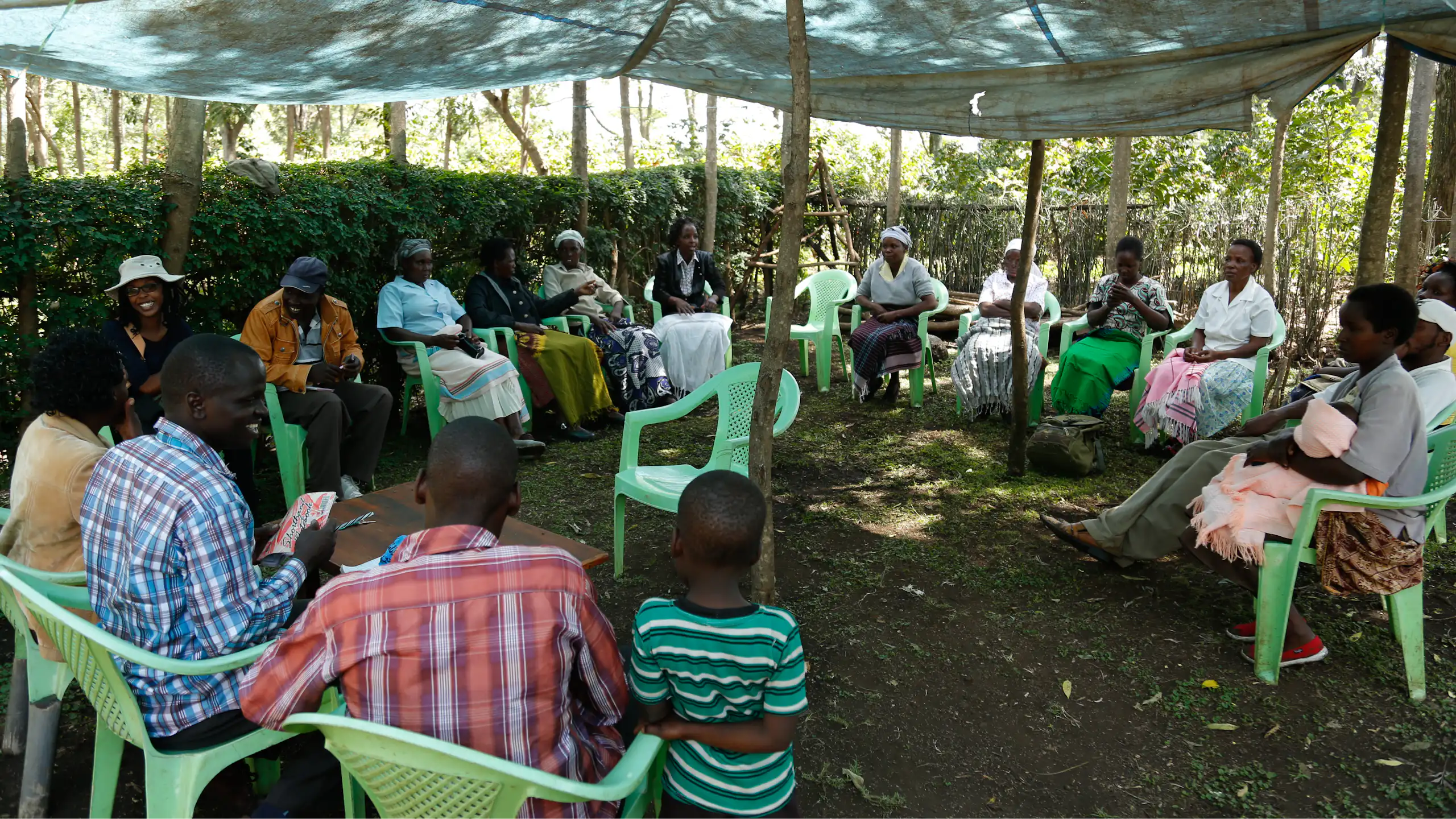 A group of people sit in a circle under an awning