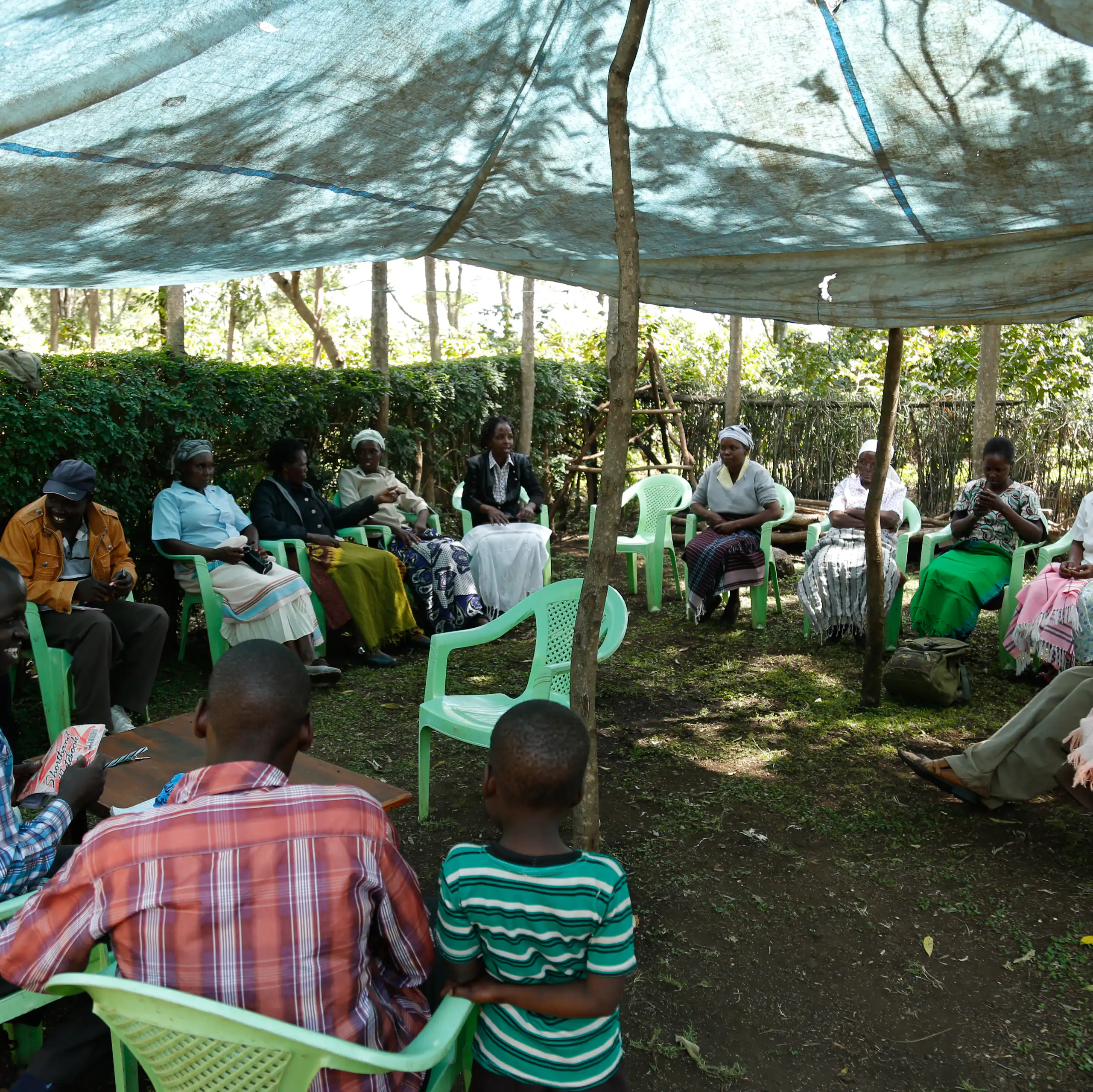 A group of people sit in a circle under an awning