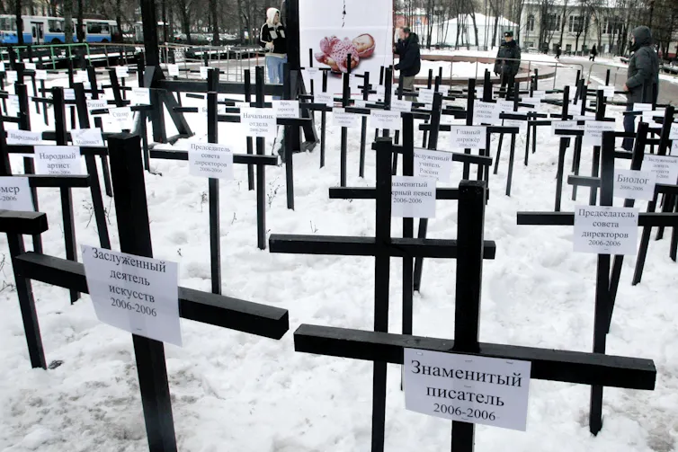 Rows of simple wooden crosses stand in snow.