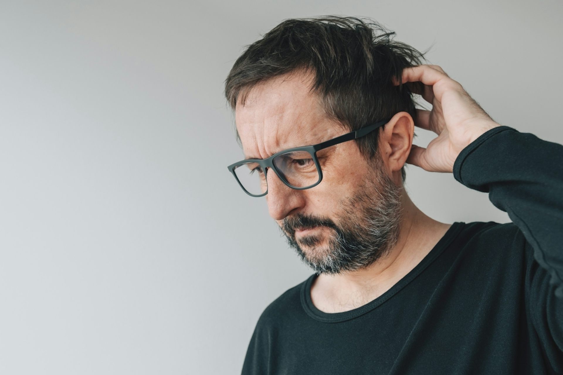 A man scratching his head, seemingly trying to remember something.