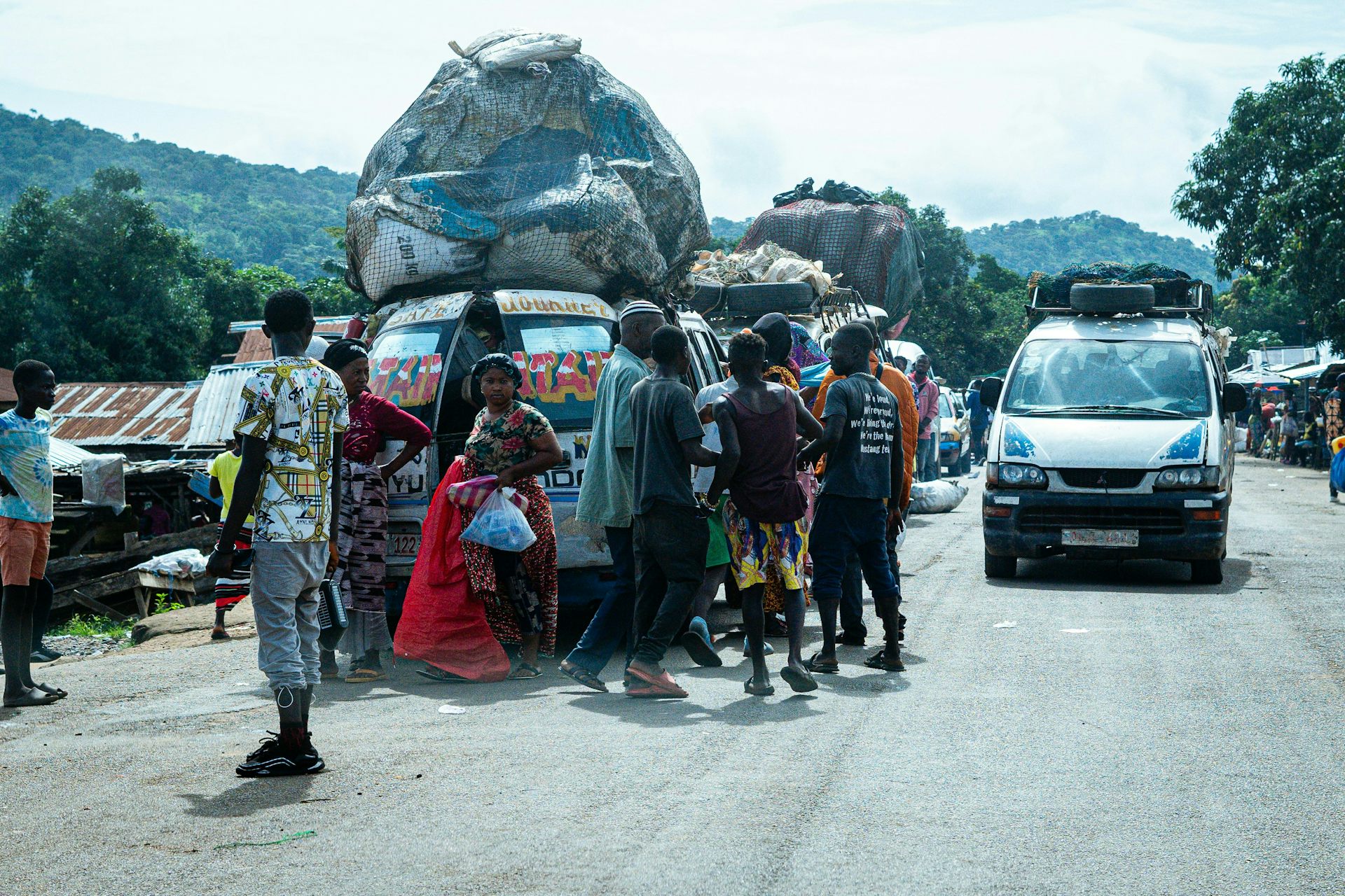 Des camionnettes chargées de matières récupérées arrivent près d'un marché achalandé dans un pays africain.