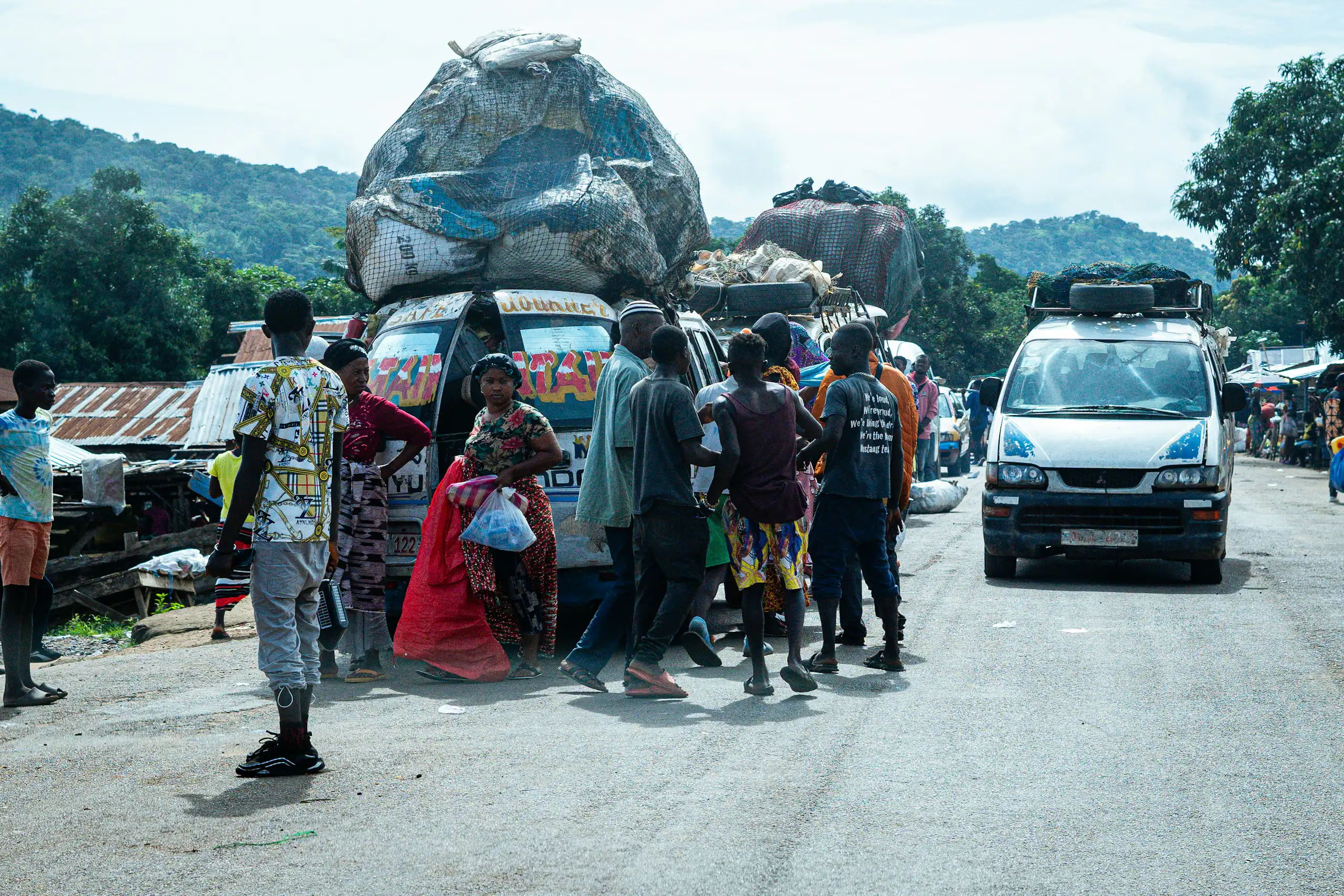 Des camionnettes chargées de matières récupérées arrivent près d'un marché achalandé dans un pays africain.
