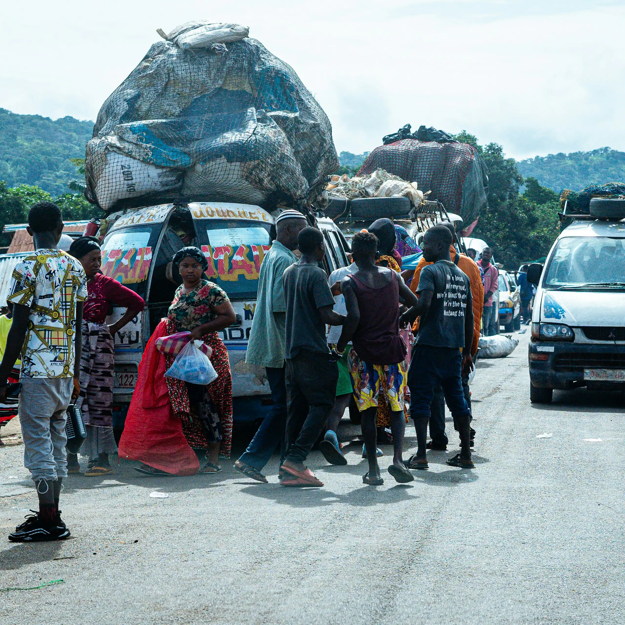 Des camionnettes chargées de matières récupérées arrivent près d'un marché achalandé dans un pays africain.