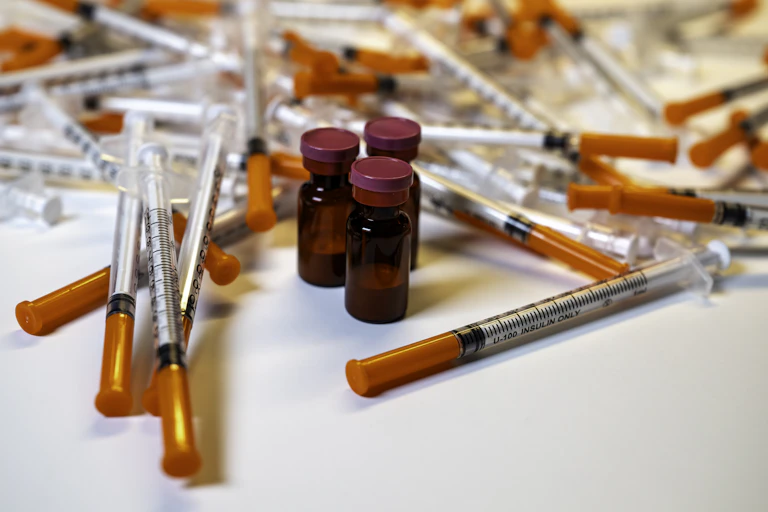 Frascos de medicamentos peptídicos rodeados por seringas.