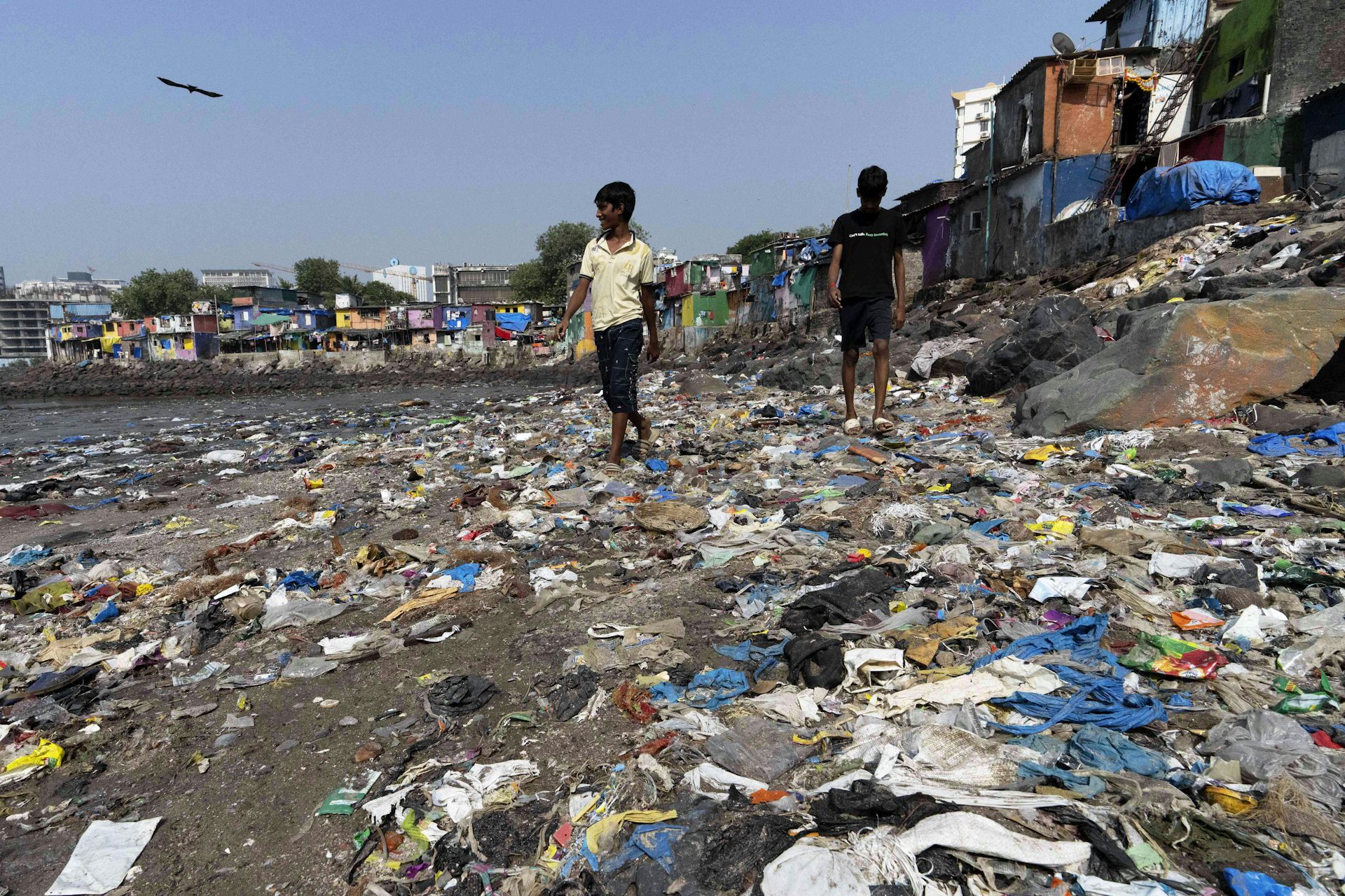 Des enfants marchent sur une rive jonchée de déchets.