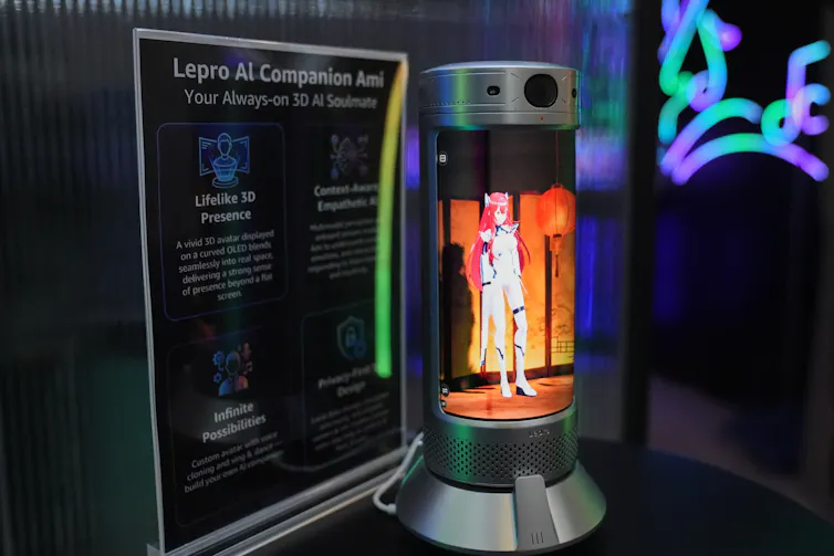 Si coqueteas con un compañero de IA, ¿eso cuenta como trampa? 1 Un muñeco parecido a un elfo se encuentra, iluminado por una luz naranja, en una cápsula, sobre una mesa para exhibiciones de tecnología.