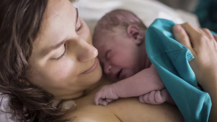 Mother cuddling newborn baby in chest
