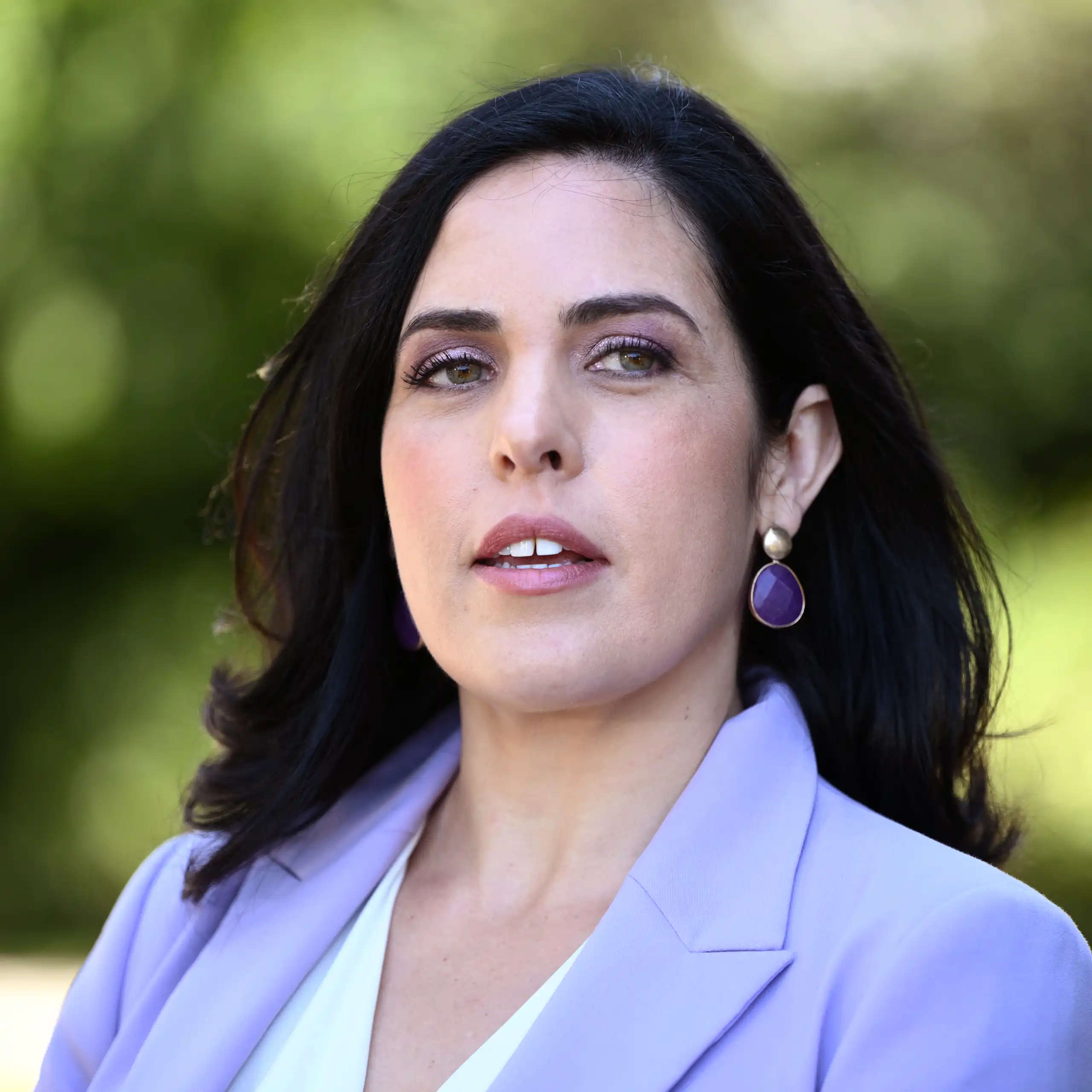 A woman in a purple blazer looks past the camera