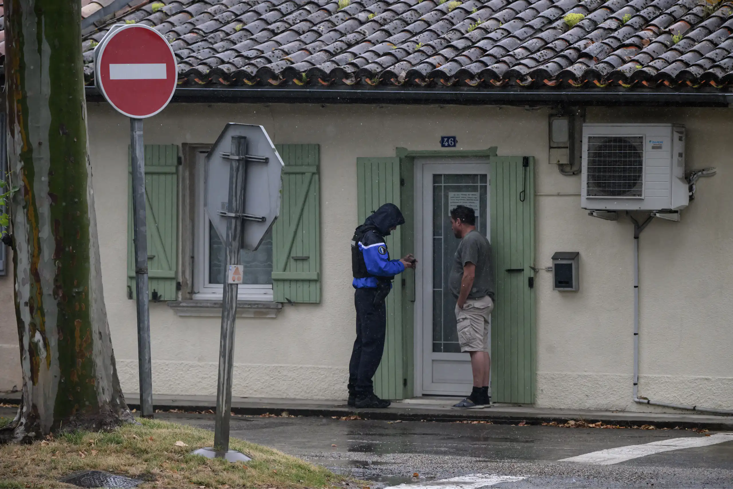 un gendarme parle avec un homme devant la porte de sa maison.